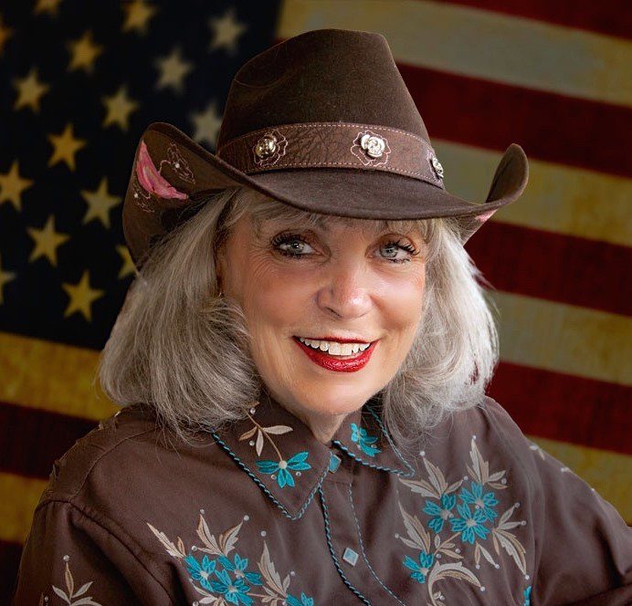 Terrie Frankel in a cowboy hat before an American flag